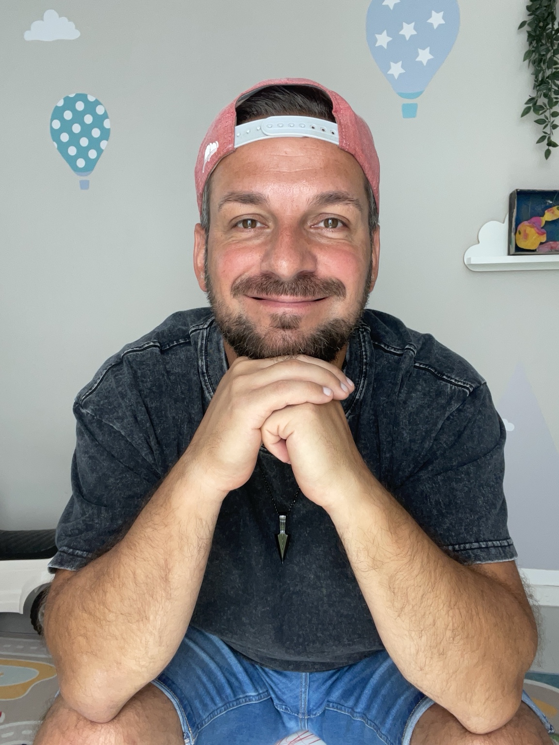 Papa Chrizz – Portrait mit leichtem Lächeln und beiden Händen unter dem Kinn
